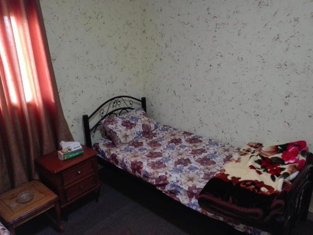 a small bedroom with a bed and a night stand at Dana INN in At-Tafilah