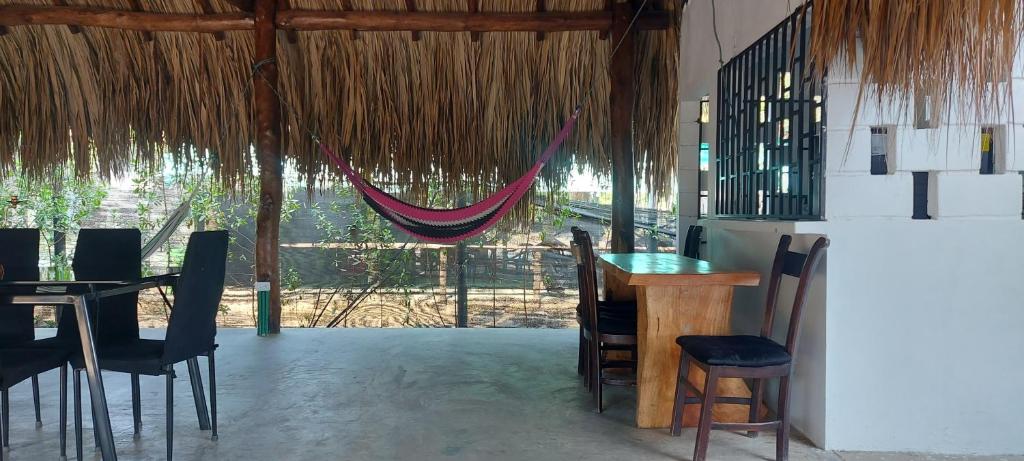 um restaurante com uma mesa e cadeiras e uma rede de descanso em Cabaña Palmeras del Viento em San Bernardo del Viento