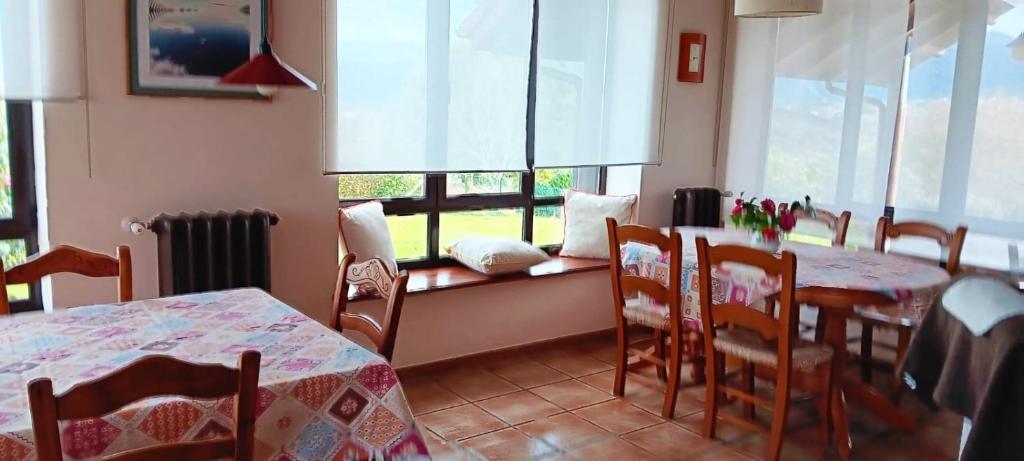 a dining room with two tables and chairs and a window at Prau del Urogallo in Ribadesella