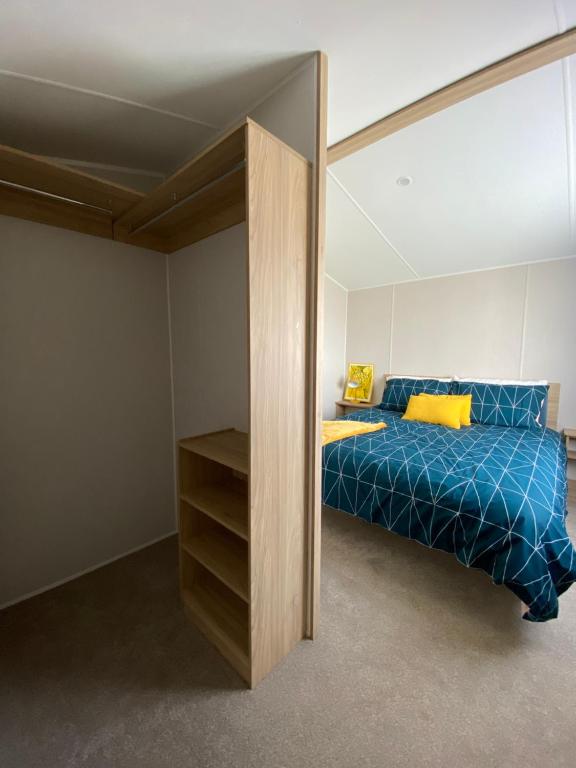 Schlafzimmer mit einem Bett mit blauer Bettwäsche und gelben Kissen in der Unterkunft VerbZen Holiday Caravan at St Osyth Beach, Clacton-on-Sea by Verb Holidays in Saint Osyth