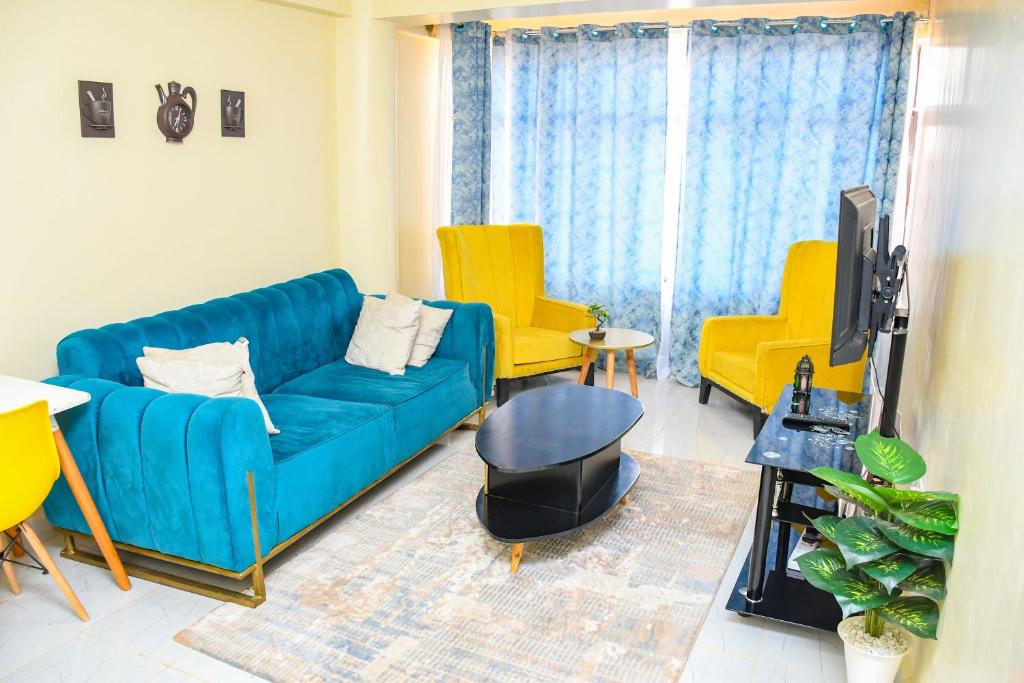 Dala Suites في Kakamega: غرفة معيشة مع أريكة زرقاء وكرسيين صفراء