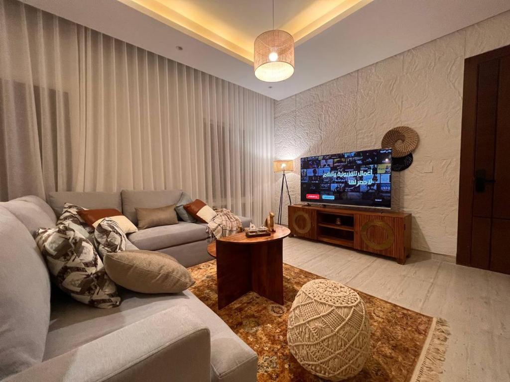 Zaya luxury apartment في الرياض: غرفة معيشة مع أريكة وتلفزيون بشاشة مسطحة