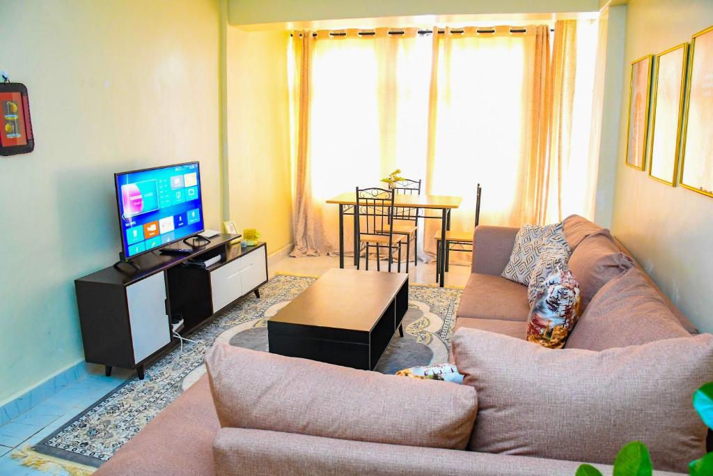 ein Wohnzimmer mit einem Sofa und einem Flachbild-TV in der Unterkunft Raven Suites in Kakamega