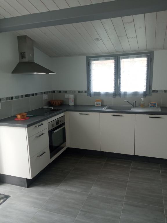 - une cuisine avec des placards blancs, un évier et 2 fenêtres dans l'établissement maison rénovée en 2022, à Barbâtre