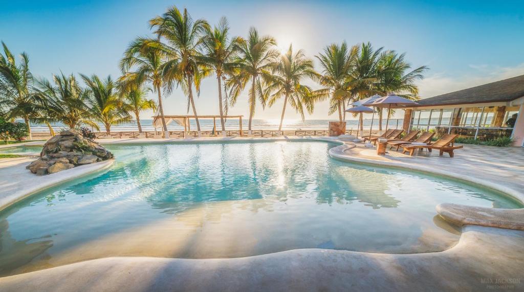 a swimming pool with palm trees in a resort at Hotel Bahía Paraíso in San Blas