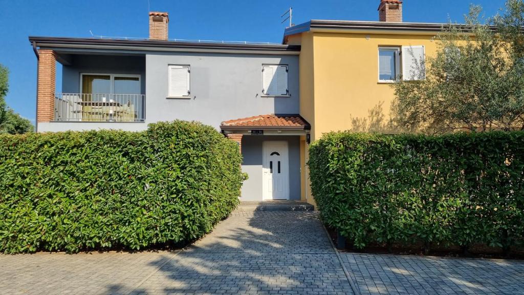 a white and yellow house with a gate and bushes at Casa Emma in Poreč