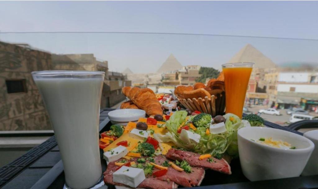 Pharaonic Pyramids Inn في القاهرة: طاولة مع طبق من الطعام وكأسين من الحليب