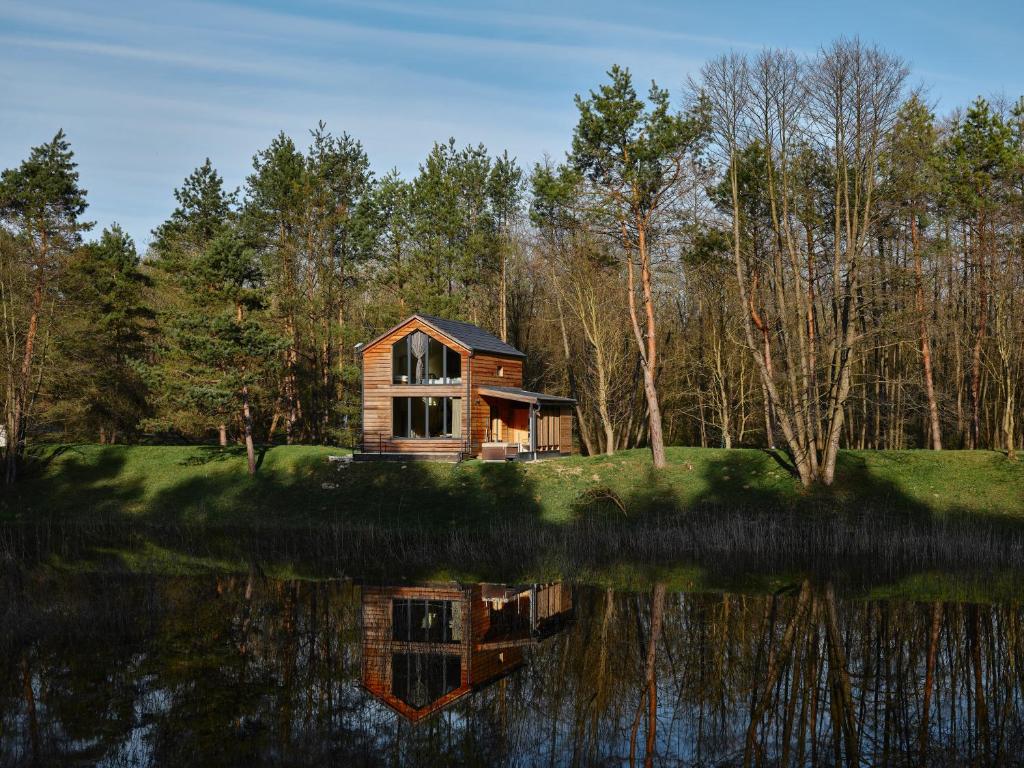 a small wooden cabin on the shore of a lake at Bakony Deep Forest Vendégház in Bakonyszentlászló