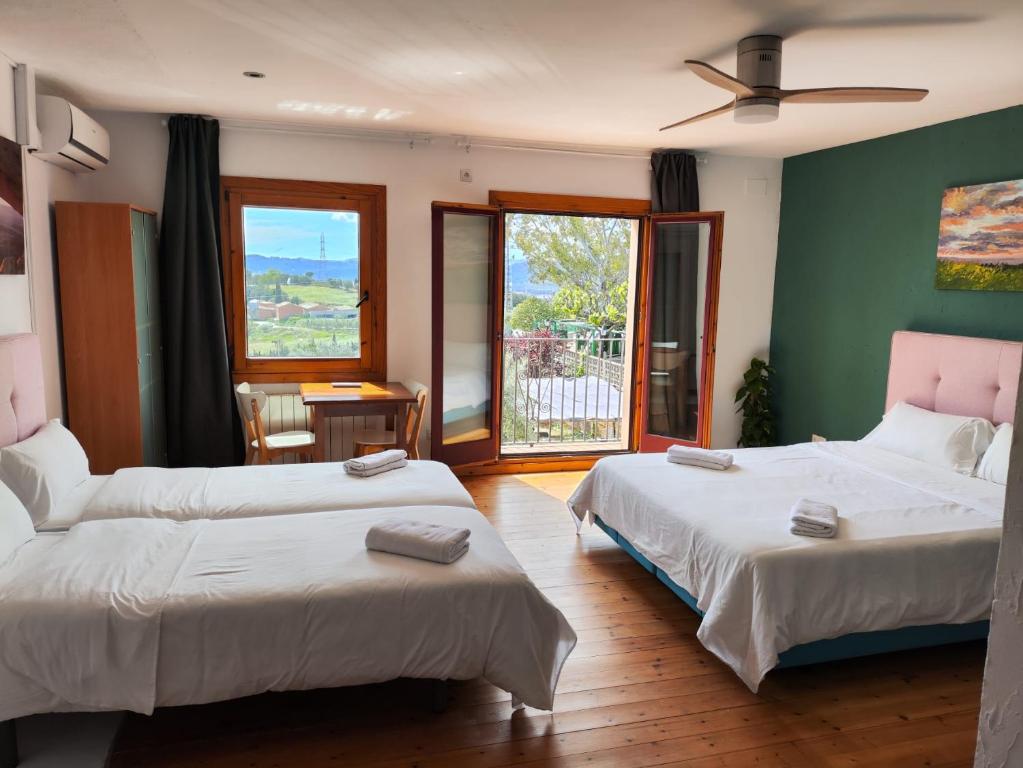 a bedroom with two beds and a window at L'Olivera Casa Rural in Castellbisbal