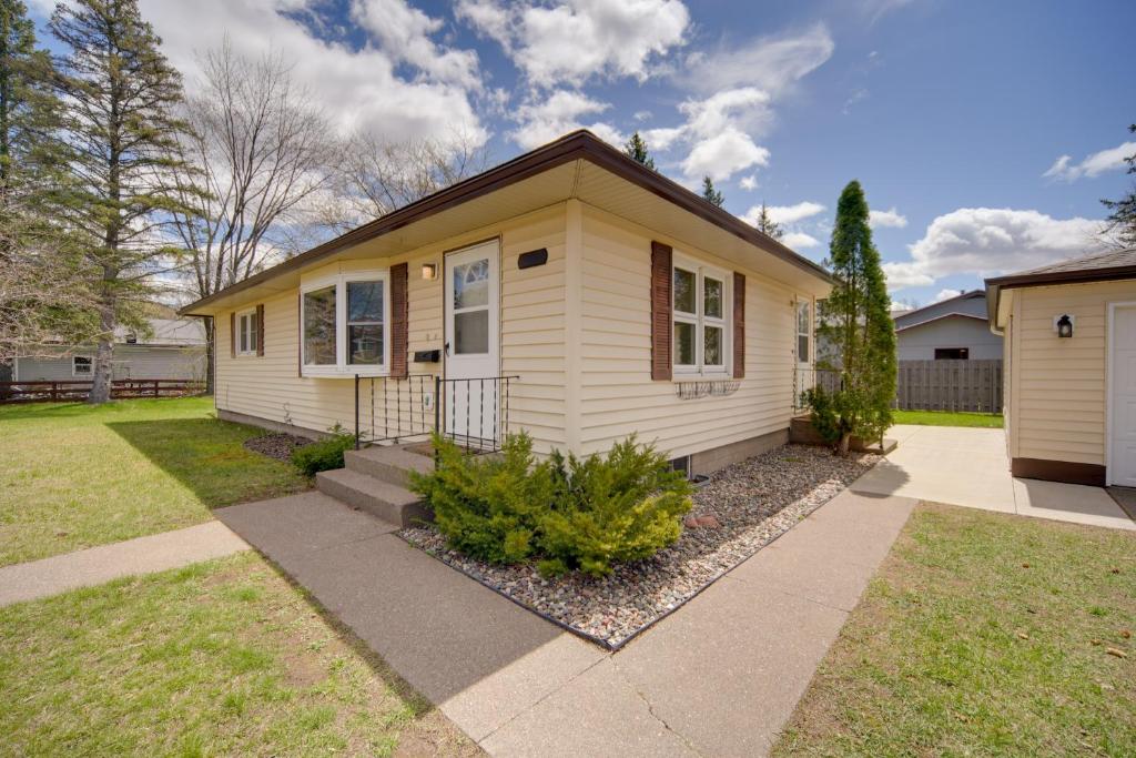 a small yellow house with a grass yard at Sunny Cloquet Home - 2 Mi to St Louis River! in Cloquet