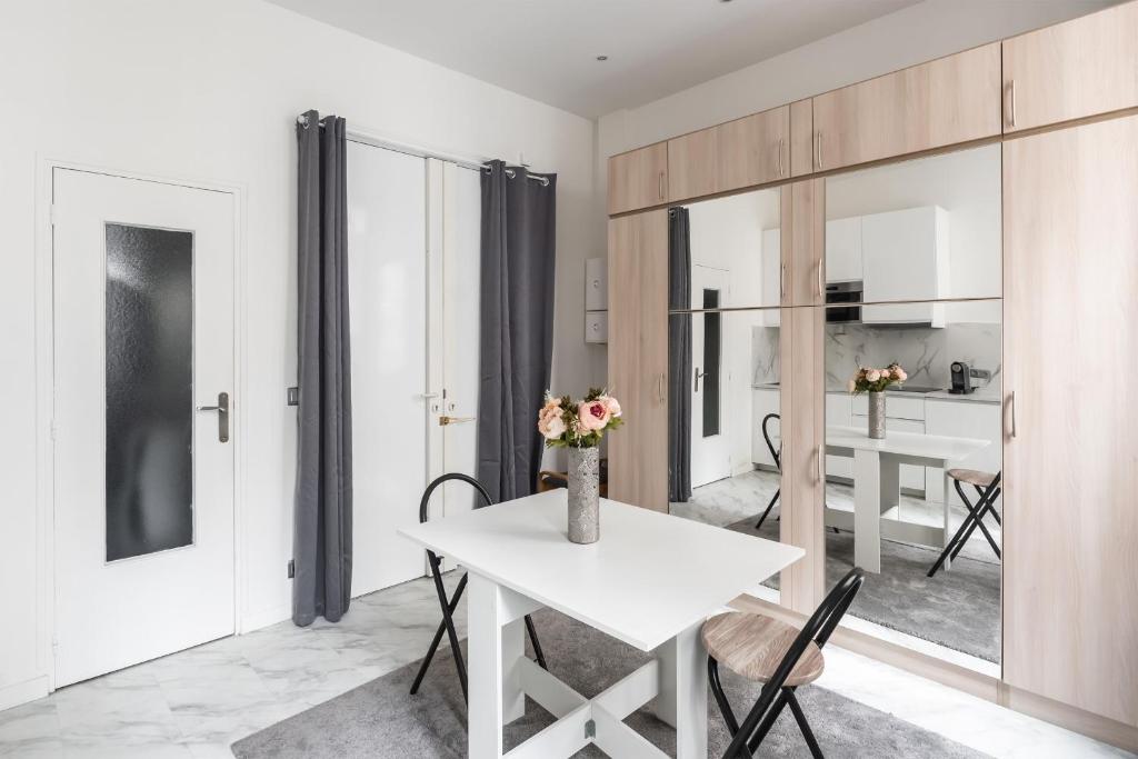 une cuisine et une salle à manger avec une table et des chaises blanches dans l'établissement Studio Exelmans - Welkeys, à Paris