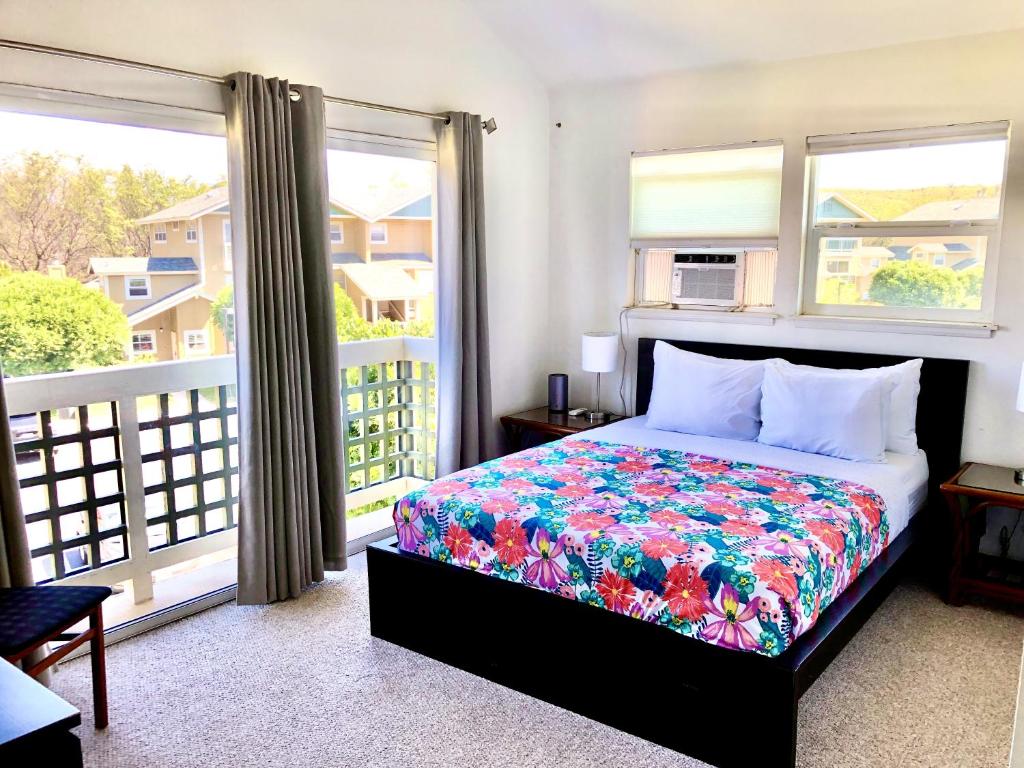 a bedroom with a bed and a balcony with windows at Waikoloa Hills #105: Pineapple Paradise in Waikoloa