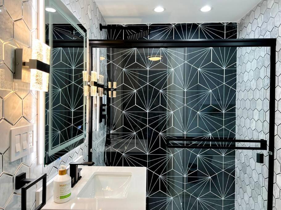 a bathroom with a black and white tiled wall at H2O Haven: 5 mins To Niagara Falls in Niagara Falls