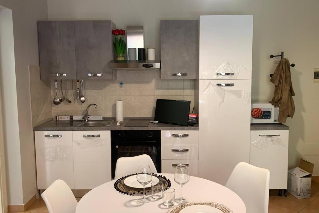 eine Küche mit einem Tisch und weißen Stühlen sowie eine Küche mit einer Theke in der Unterkunft NEST HOUSE - ESCLUSIVO APPARTAMENTO Marina di Olbia- MATER OLBIA - Beaches - close to the Airport - PRIVATE PARKING- Full comforts - in Olbia