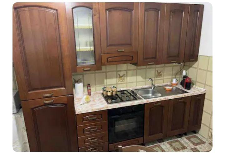 uma cozinha com armários de madeira e um lavatório em La Zàgara em Realmonte