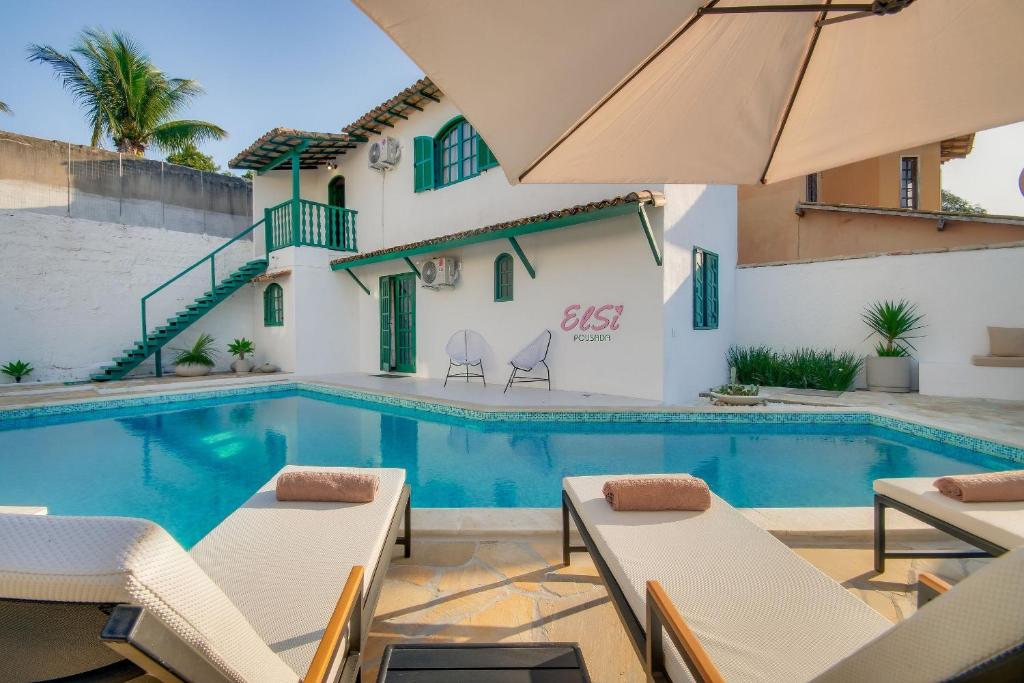a villa with a swimming pool with chairs and an umbrella at Elsi Pousada in Búzios