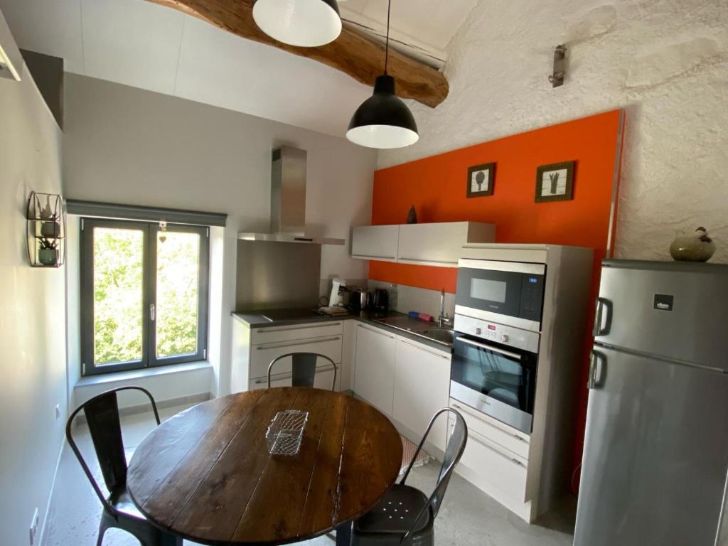 a kitchen with a wooden table and an orange wall at L’ Annexe in Chariez