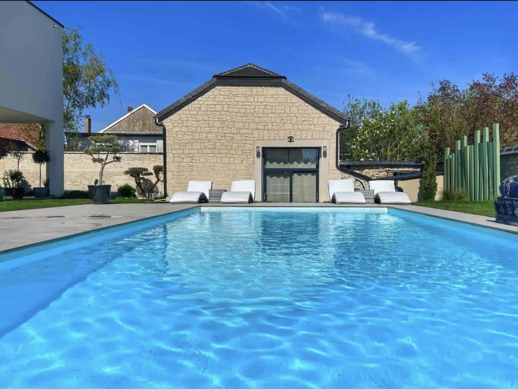 a swimming pool with chairs and a house at Magnifique grange rénovée au coeur de la Champagne in Les Mesneux