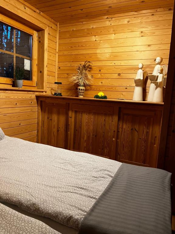 1 dormitorio con 1 cama y pared de madera en Domek z bali Tryszczyn nad Brdą, en Tryszczyn