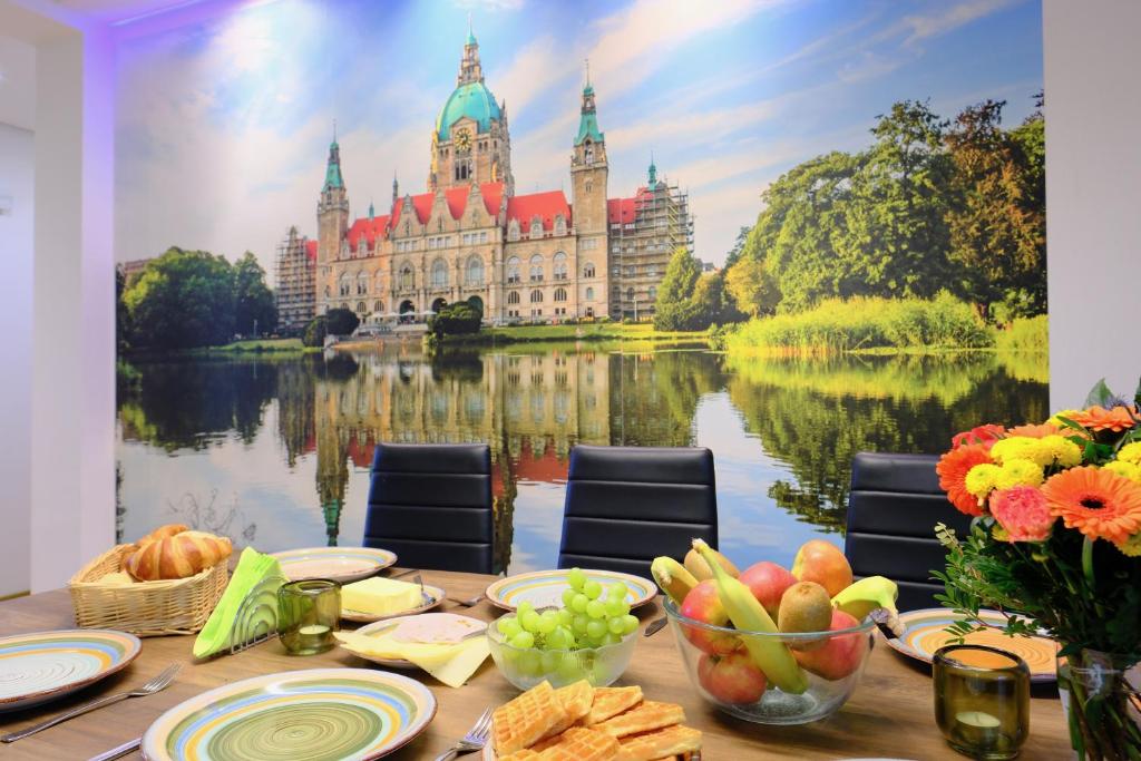 a table with food and a large building on the water at HappyBnB - Stilvolles, naturgelegenes Apartment mit Blick auf den Mittellandkanal und die Wasserstadt Hannover - Kamin, Parken und Spielplatz in Hannover