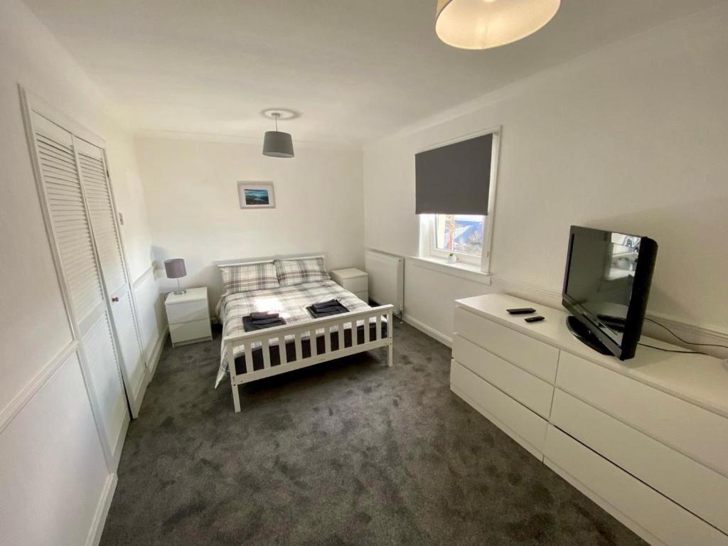 a small white room with a bed and a tv at Fort William - Highland holiday home in Fort William