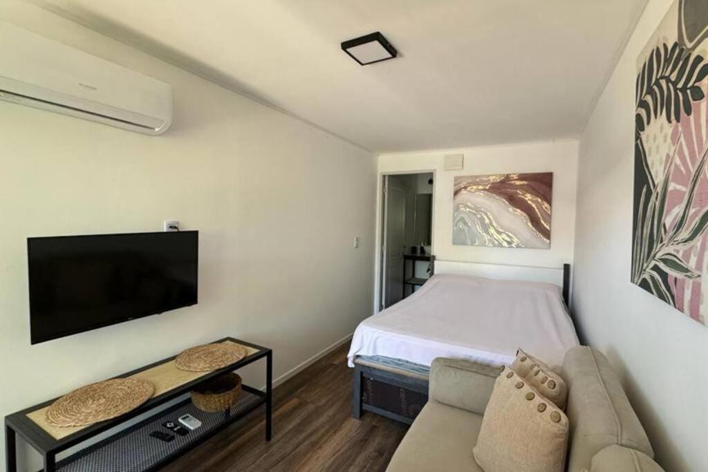 een kleine slaapkamer met een bed en een bank bij Monoambiente Moderno in Cuchilla Alta