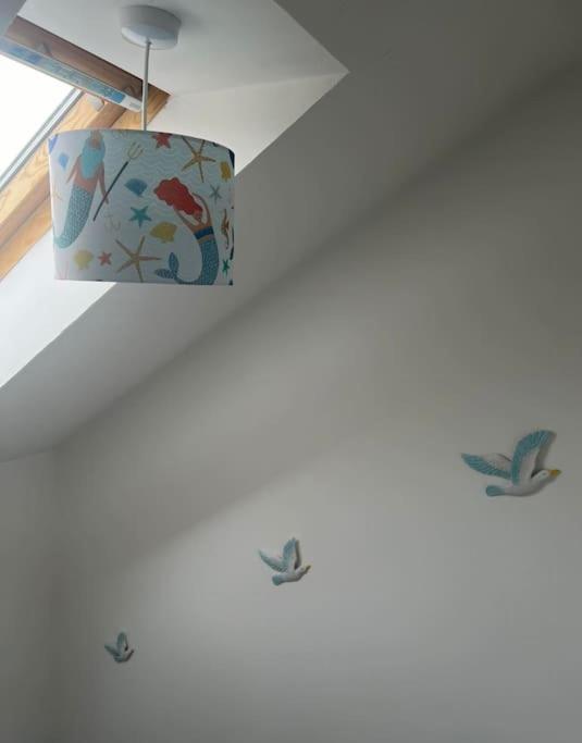 a light hanging from a ceiling with birds on it at Annie's Hideaway in Chapel Saint Leonards