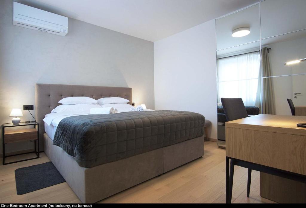 a bedroom with a large bed with a desk and a desk at Val De Laco studio apartments in Rovinj
