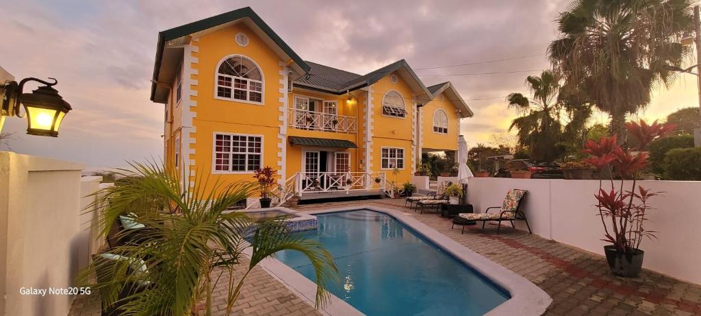 una casa amarilla con piscina frente a ella en Faith's Villa Tobago, en Diamond