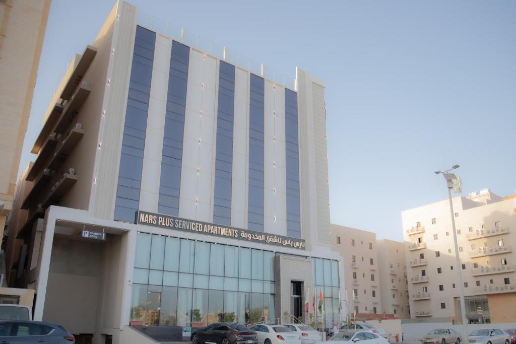 ein großes Gebäude mit Autos auf einem Parkplatz in der Unterkunft فندق نارس بلس النزهة - Nars Plus Hotel in Dschidda