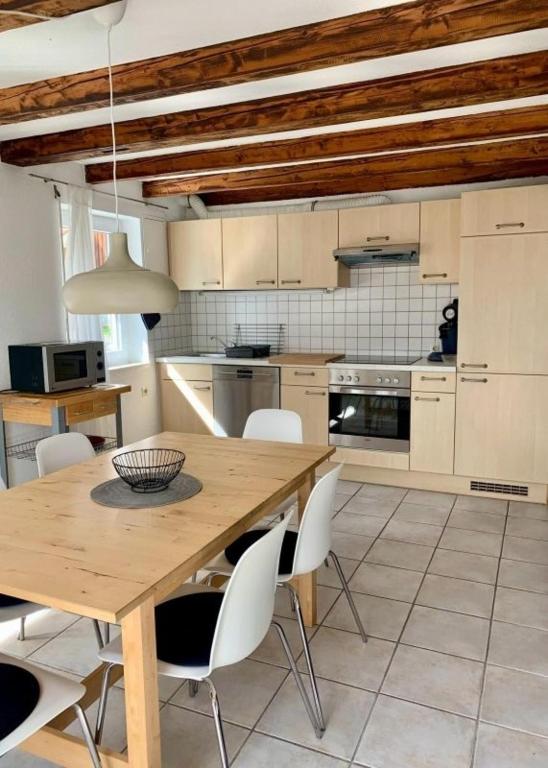 a kitchen with a wooden table and white chairs at Haus Alkmene in Bodman-Ludwigshafen