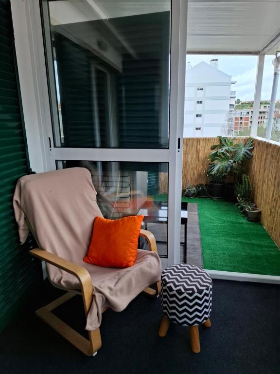 uma cadeira de baloiço com uma almofada laranja na varanda em Lisbon Hideaway Haven em Lisboa