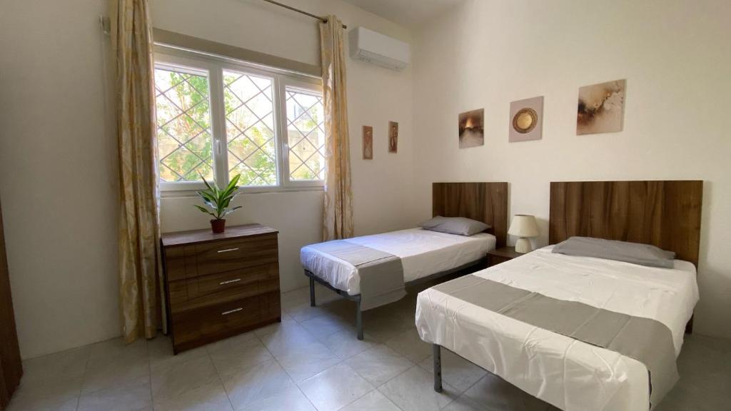 Spacious room with 2 single beds shared bathroom, st Julians في Tal-Għoqod: غرفة نوم بسريرين ونافذة