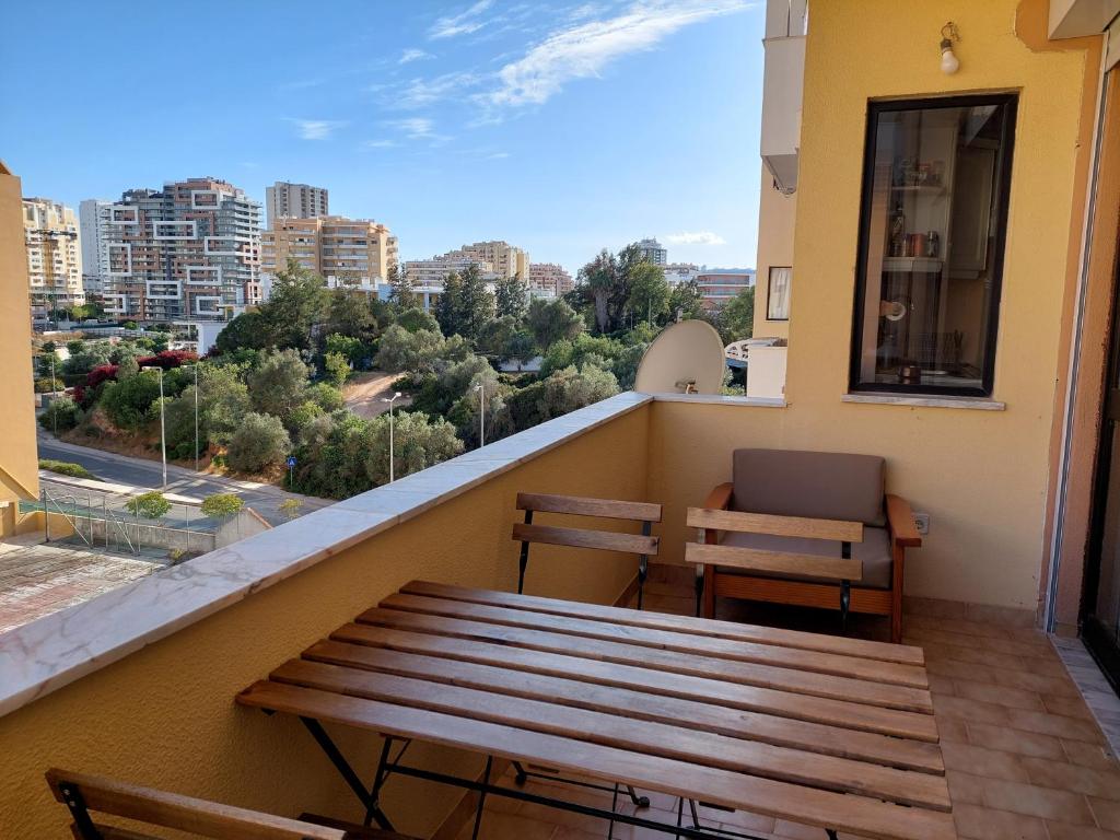 een balkon met een houten bank en een tafel bij Alltravel pátio da rocha in Portimão