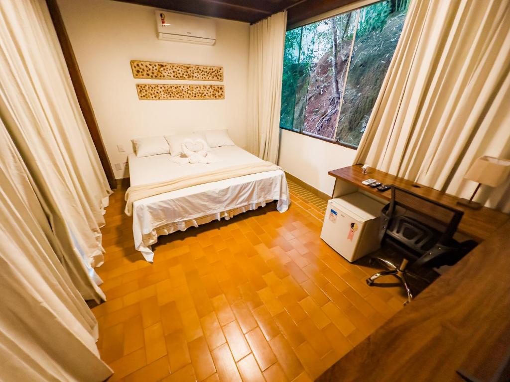 a bedroom with a bed and a desk and a window at Pousada Casa de Charme in Lençóis