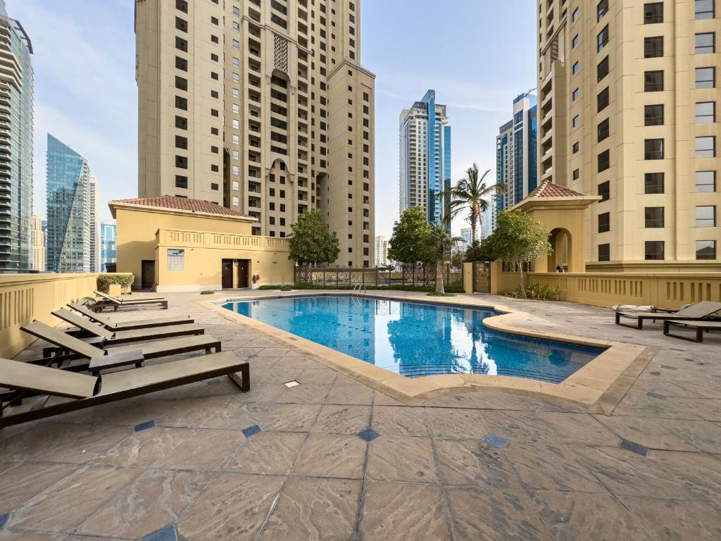 a pool in the middle of a city with tall buildings at JBR Beach, The Walk, 1-BDR with pool view in Dubai