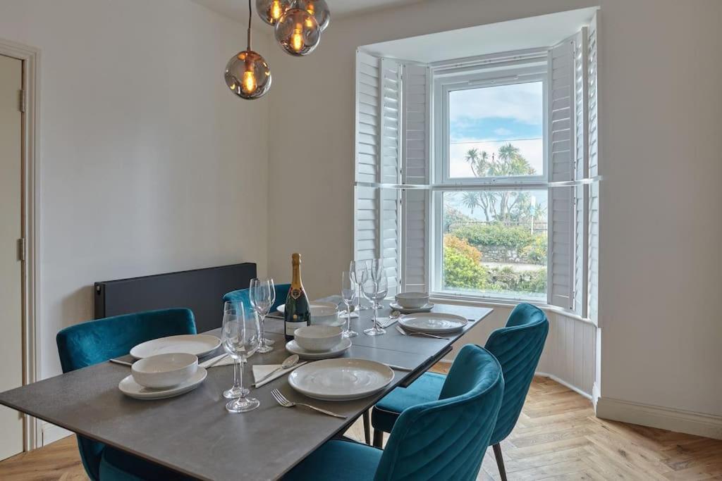a dining room table with blue chairs and a window at Modern house in Carbis Bay in Carbis Bay