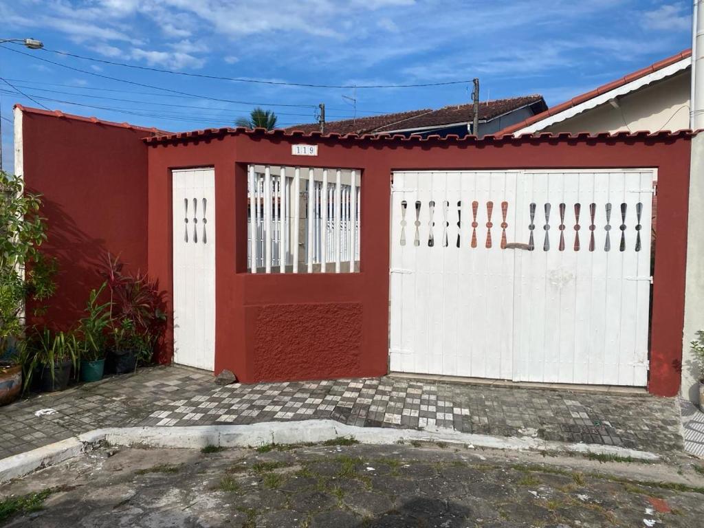 uma garagem vermelha e branca com uma porta vermelha em Casa do lado da praia, 100 metros da praia. em Mongaguá