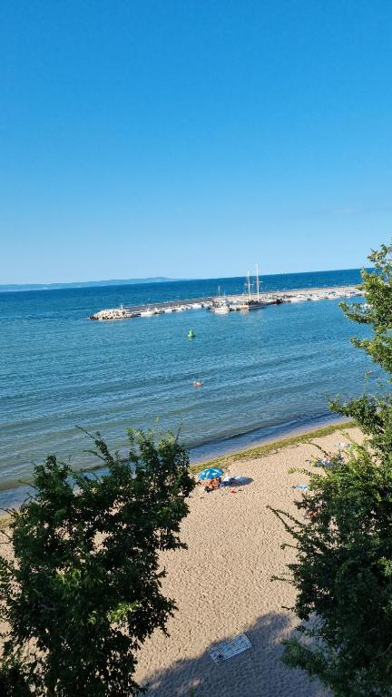 - une plage avec des arbres et l'océan avec des bateaux dans l'établissement Студия първа линия Черноморец, à Tchernomorets