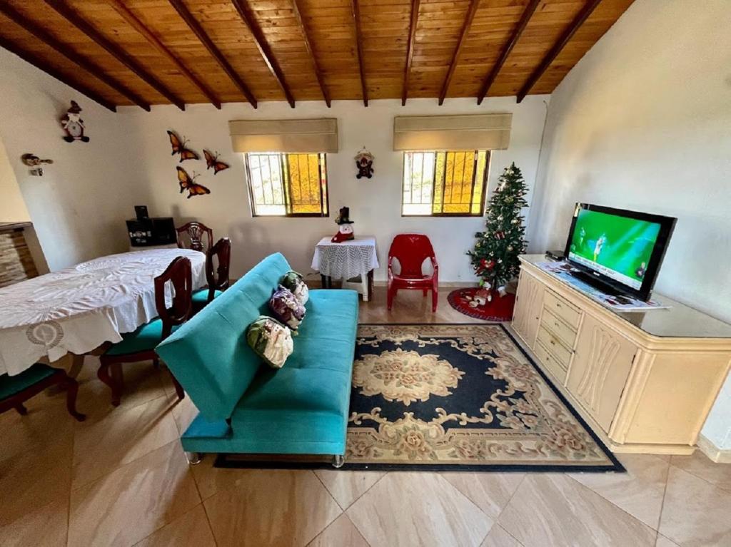 a living room with a television and a couch and a christmas tree at Condominio Portal del Sol, Cabaña en la Mesa de los Santos in Los Santos