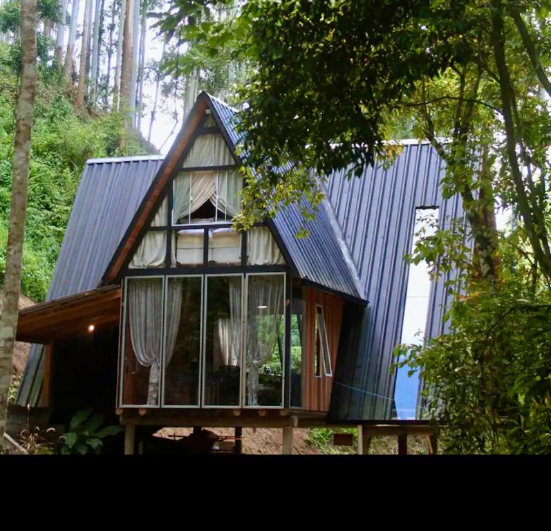 una pequeña casa con techo azul y ventanas en Chalé Romântico com cachoeira, en Witmarsum
