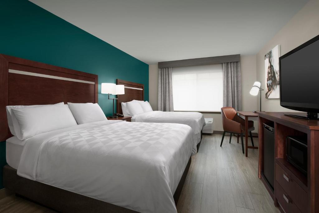 a hotel room with two beds and a flat screen tv at Holiday Inn & Suites Durango Downtown by IHG in Durango