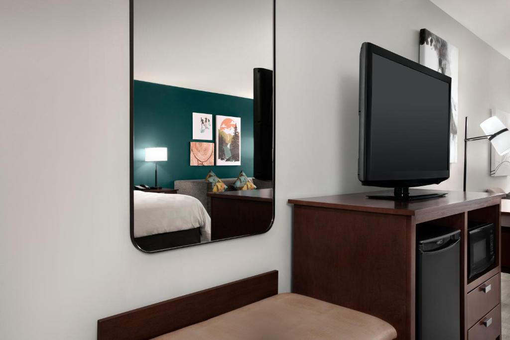 a room with a television on a dresser with a mirror at Holiday Inn & Suites Durango Downtown by IHG in Durango