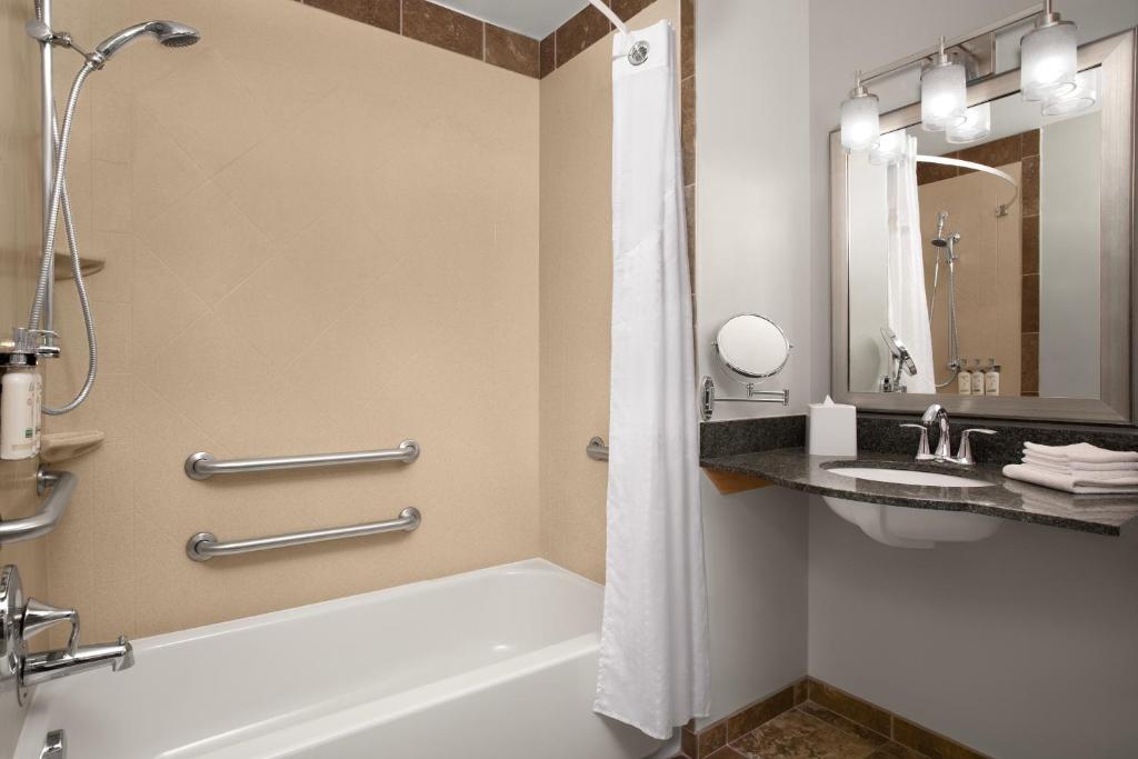 a bathroom with a tub and a shower and a sink at Holiday Inn & Suites Durango Downtown by IHG in Durango