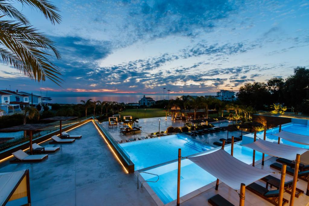 vista para uma piscina num resort ao anoitecer em Cavo Zoe Seaside Hotel em Protaras