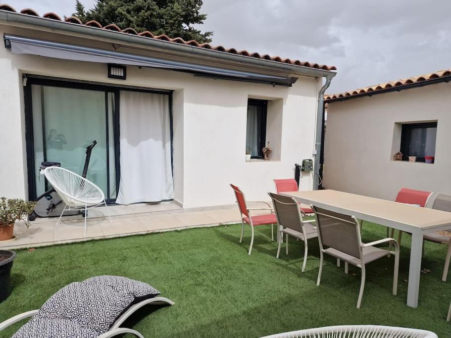 un patio avec une table et des chaises sur l'herbe dans l'établissement Rognac centre au calme maison entiere 5 couchages et jardin, à Rognac