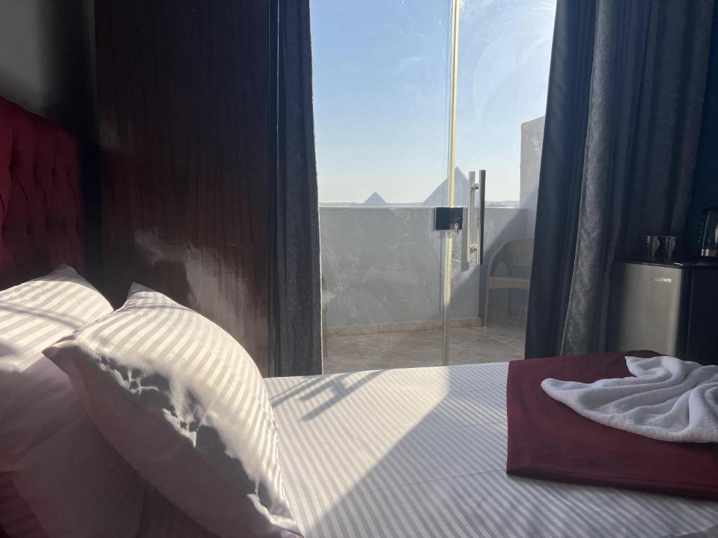 a bedroom with a bed and a large window at Orion pyramids view in Cairo