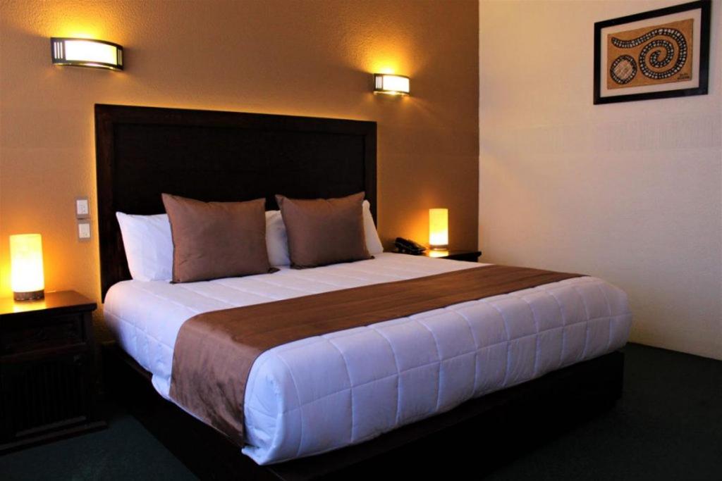 un grande letto in una camera d'albergo con due lampade di Hoteli Alifer Tlaxcala X TECAL LIVING a Tlaxcala de Xicohténcatl