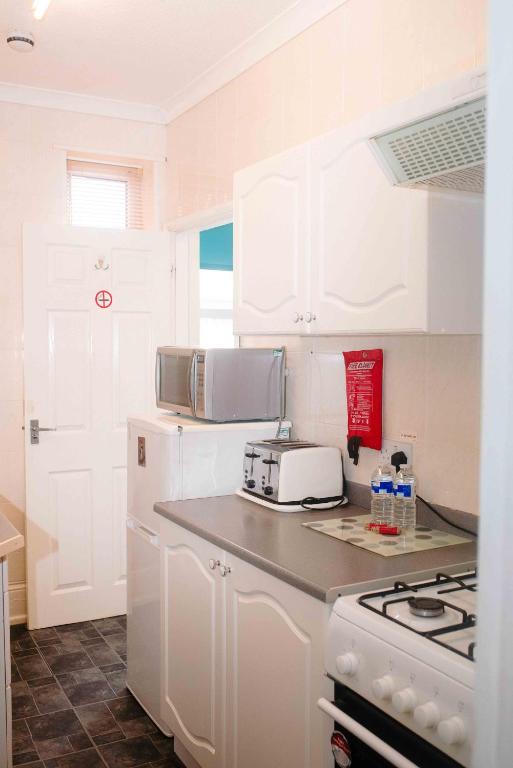 a kitchen with white cabinets and a white refrigerator at THE CHADWICK in Skegness