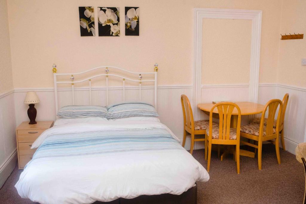 a bedroom with a bed and a table with chairs at THE CHADWICK in Skegness